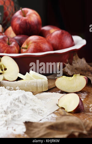 Ancienne en bois rouleau à pâtisserie saupoudrée de farine blanche sur une table rustique. Tarte aux pommes Ingrédients des pommes et beurre dans l'arrière-plan. dept peu profondes extrêmes Banque D'Images