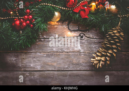 Noël arrière-plan - Garland, Golden et ornements rouge et de pin sur fond de bois foncé Banque D'Images