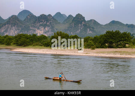 Un pêcheur l'aviron un radeau en bambou à Guilin, Chine. Banque D'Images