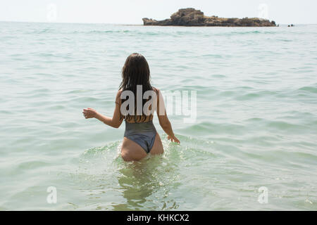 Vue arrière d'une femme en bikini dans la mer à pied Banque D'Images