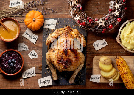 Capture d'un grand angle d'un dindon rôti sur une table en bois à côté de certains autres aliments et quelques morceaux de papier avec des mots tels que la famille, reconnaissant, souvenirs, ho Banque D'Images