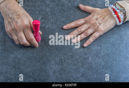 Manucure. vieille femme mains ongles polissage avec du vernis à ongles rouge en instituts de beauté. Banque D'Images