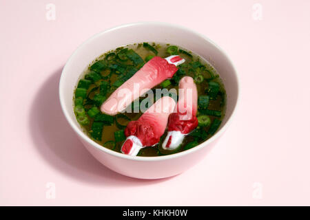 Les doigts d'un bouillon de viande avec des oignons verts flottant à la surface de la soupe dans un bol rose. Couleur du dégradé. Minime et la photographie originale. Banque D'Images