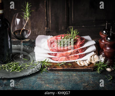 Steaks avec herbes et épices et vin rouge sur de tables de cuisine, la cuisine de préparation au fond de bois Banque D'Images