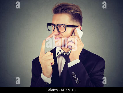 Jeune homme rusé avec long nez talking on mobile phone isolé sur fond de mur gris. menteur concept. L'émotion humaine sentiments Banque D'Images