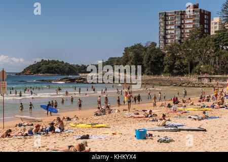 Sydney, Australie - 26 mars 2017 : section de Manly Beach avec du sable et de la mer de Tasman. les gens sur le sable et dans l'eau. tour de condominiums et vert Banque D'Images