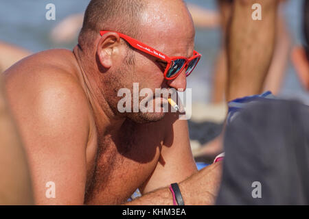 Nice , France - 5 août 2017 : homme barbu grave fumer une cigarette sur la plage. close-up portrait Banque D'Images