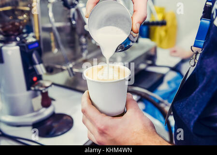 Machine à café barista, à l'aide de la préparation du café frais et verser le lait pour faire le café espresso latte art en papier blanc tasse à café. Selective Banque D'Images
