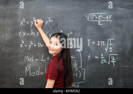 Belle asiatique student writing on blackboard with chalk en classe. Banque D'Images