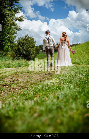 Photo d'un jeune couple marchant dans un chemin à travers un parc se tenant la main. Banque D'Images