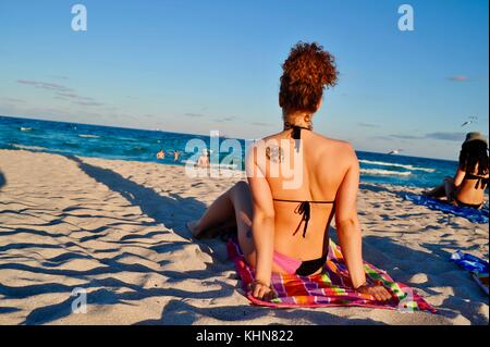 Belles femmes soleil sur plage en fin d'après-midi à South Beach, Miami, Floride, USA. Banque D'Images