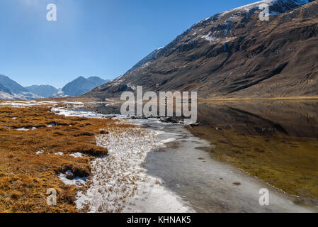 Vue panoramique sur la montagne paysage d'automne avec un lac, des montagnes se reflétant dans le lac, avec la neige et de la glace sur la rive sur une journée ensoleillée Banque D'Images