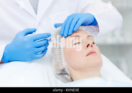 Ce chirurgien plastique injection de botox dans le temple de son patient vieillissement Banque D'Images