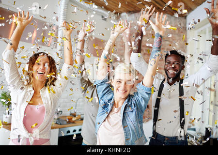 Les jeunes adolescents gais dans casualwear dancing Noël sous la pluie de confettis Banque D'Images