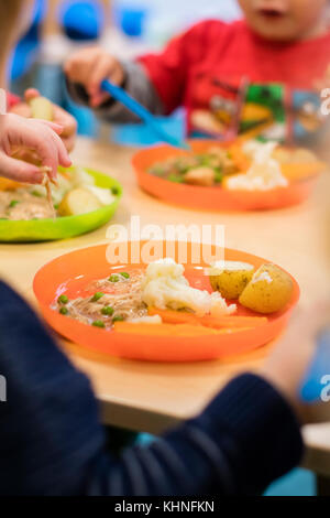L'école d'avant garde pour les jeunes enfants : les jeunes enfants de manger leur repas à l'heure du dîner dans une crèche maternelle dans le pays de Galles UK Banque D'Images