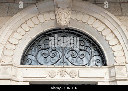 Un linteau de pierre, installé dans une fenêtre supérieure semi-circulaire, avec une grille en fer stylisée d'une porte d'une maison arabe qui a été abandonnée en 1948 dans le quartier de Musrara également connu sous son nom hébreu, Morasha dans Jérusalem-Ouest Israël Banque D'Images