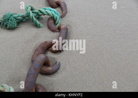 Vieux bateau rouillé avec une chaîne corde turquoise attaché à lui sur une plage de sable avec une faible profondeur de champ Banque D'Images