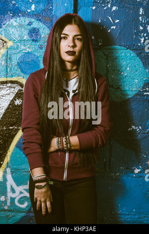 Un style grunge et dark haired woman avec un hooded Sweat rouge Banque D'Images