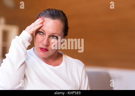 Portrait d'une femme d'âge moyen souffrant de maux de tête dans son appartement au dernier étage. Banque D'Images