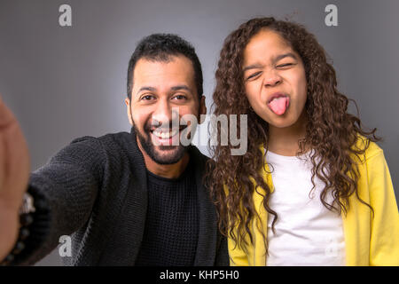 Vue caméra d'un père noir et de sa jeune fille prenant des selfies tout en faisant des visages drôles Banque D'Images