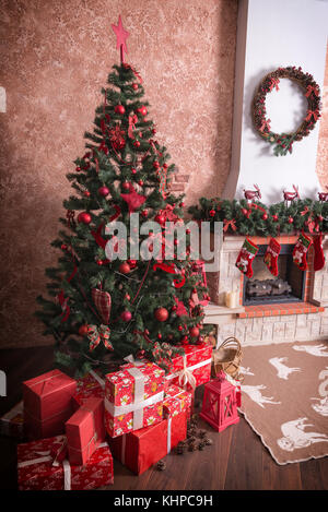 Nombre de boîtes avec des cadeaux de Noël sous l'arbre de Noël près de la cheminée. Banque D'Images