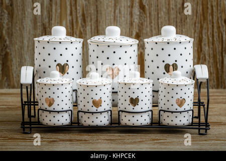 En porcelaine blanche pointillée noire spice jars avec motif coeur sur fond brun Banque D'Images