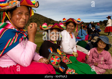Plusieurs femmes du village de Llachón vêtues de costumes régionaux traditionnels assistent à un match de football en public. Péninsule de Capachica, près de Puno Banque D'Images