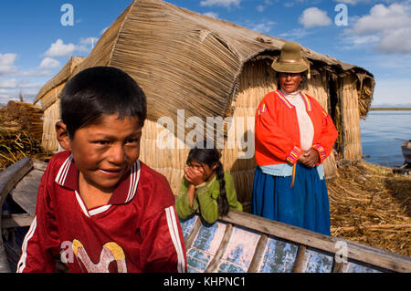 Île d'Uros, lac Titicaca, pérou, Amérique du Sud. Une famille autour de sa maison, faite de totora, sur une des îles Uros. Banque D'Images