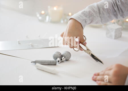 La photo en gros plan de l'enfant tenue de coupe ciseaux, papier blanc, la création d'origami papier de noel Banque D'Images