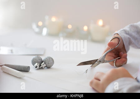 La photo en gros plan de l'enfant tenue de coupe ciseaux, papier blanc, la création d'origami papier de noel Banque D'Images