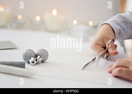 La photo en gros plan de l'enfant tenue de coupe ciseaux, papier blanc, la création d'origami papier de noel Banque D'Images