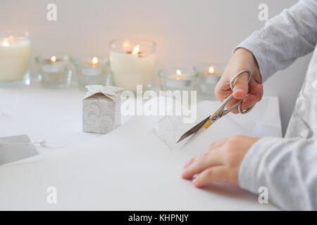 La photo en gros plan de l'enfant tenue de coupe ciseaux, papier blanc, la création d'origami papier de noel Banque D'Images