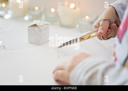 La photo en gros plan de l'enfant tenue de coupe ciseaux, papier blanc, la création d'origami papier de noel Banque D'Images