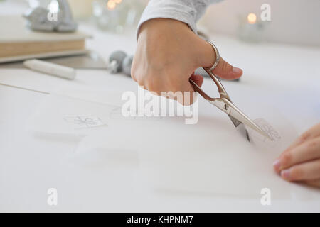 La photo en gros plan de l'enfant tenue de coupe ciseaux, papier blanc, la création d'origami papier de noel Banque D'Images