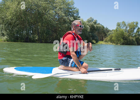 En contemplant la nature attractive mature rider assis sur paddle board Banque D'Images