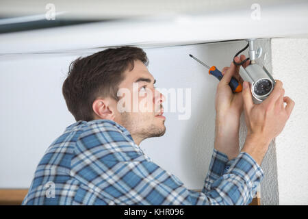 Jeune homme entrepreneur installation camera de surveillance Banque D'Images