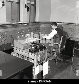Années 1950, historiques, homme railway signal conducteur assis à la table de contrôle, la Rhodésie, l'Afrique. Le signal du matériel a été fourni et installé par le fabricant britannique, Siemens et General Electric Railway Signal Company basée à Wembley, Londres, Angleterre, Royaume-Uni. Banque D'Images