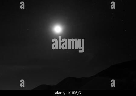 La lune avec un pic de derrière un cloudscape la nuit en noir et blanc. Banque D'Images