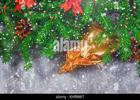 Branches de sapin avec les cônes et arcs rouge sur un fond de béton gris. nouvelle année. Noël sac d'or avec des cadeaux Banque D'Images