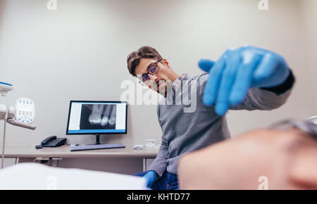 Dentiste mâle femelle pour positionner patient demandant sa bouche pour x-ray en clinique. L'examen des dents Stomatologist patiente. Banque D'Images