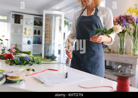 Femme habile création fleuriste bouquet de fleurs. Fleuriste fleurs jeune femme coupe avec des ciseaux et de la conception de bouquet sur comptoir à l'atelier. Banque D'Images