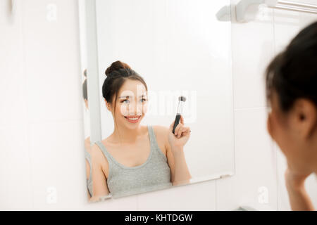 Belle femme appliquant le maquillage blush dans sa salle de bain Banque D'Images