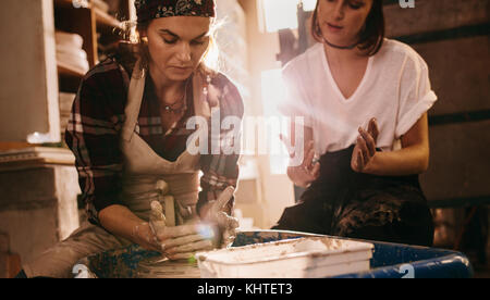 Femme potter enseignement de l'art de faire de pot. Deux femmes dans un atelier de poterie faire des pots d'argile. Banque D'Images