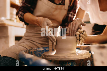 Femme potter enseignement de l'art de faire de pot. Les femmes qui travaillent sur des objets en argile de potier. Banque D'Images