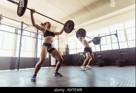 personnes de fitness à la salle de gym effectuant des exercices de soulevé de terre avec barre de poids. Homme et femme faisant des exercices d'haltérophilie au gymnase. Banque D'Images