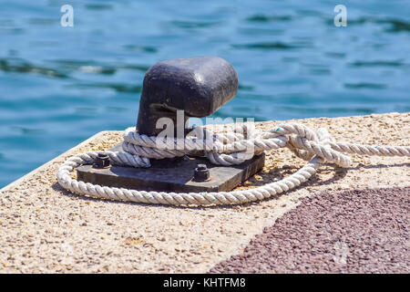 Vieux métal pole avec anneau d'amarrage dock et la corde pour sécuriser les bateaux de pêche Banque D'Images