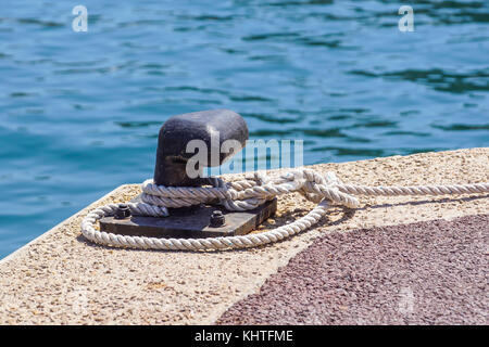 Vieux métal pole avec anneau d'amarrage dock et la corde pour sécuriser les bateaux de pêche Banque D'Images