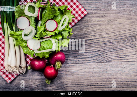 Vitamine rafraîchissante Salade. salade, les radis et les oignons de printemps sur fond de bois. avec l'espace vide pour votre texte. Vue de dessus. Banque D'Images