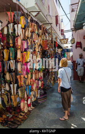 Asilah, Maroc - 14 août 2013 : jeune femme de nombreuses chaussures de cuir à vendre à street Banque D'Images