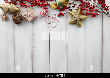 Les jouets de Noël, winterberry houx, cadeaux et coffrets cadeaux enveloppés dans du papier kraft blanc sur fond de bois, copy space Banque D'Images